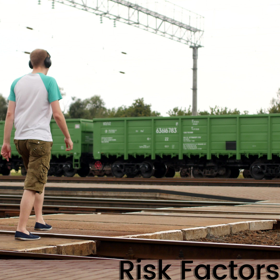 Man wearing headphones walking across railroad tracks.